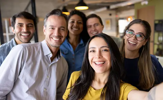 Un groupe de collaborateurs souriants pour une photo qui représente un fort lien social au travail.